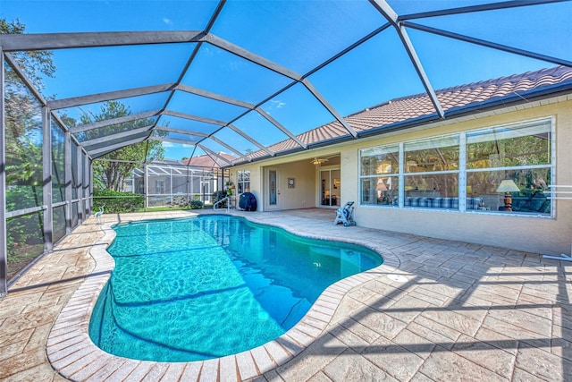 view of swimming pool featuring glass enclosure, a patio area, and ceiling fan