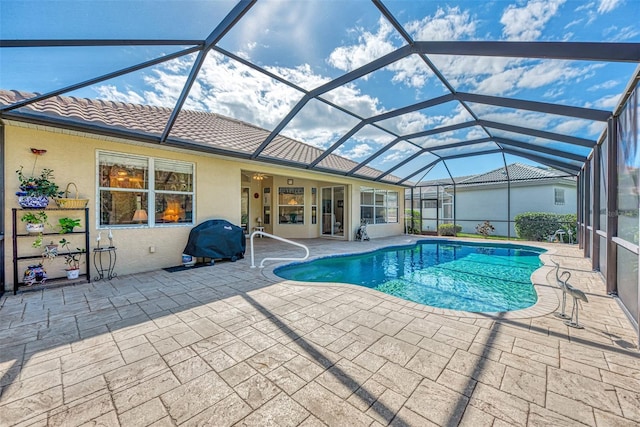 view of pool with glass enclosure and a patio area