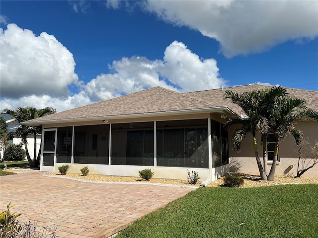 rear view of house featuring a sunroom and a lawn