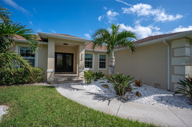 entrance to property with a garage, crawl space, french doors, and stucco siding