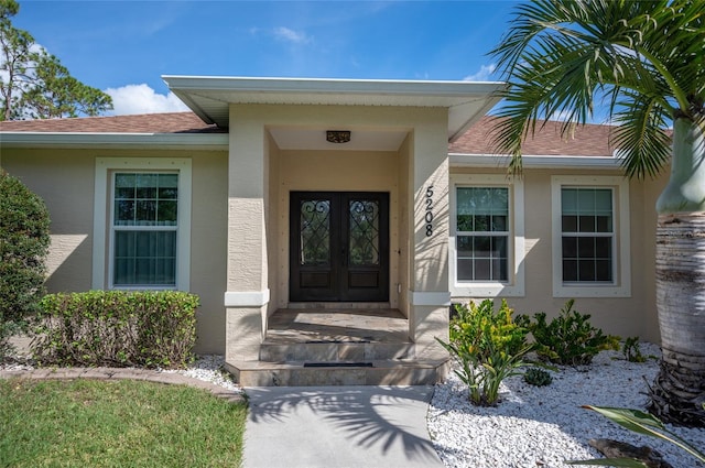 property entrance with roof with shingles, french doors, and stucco siding