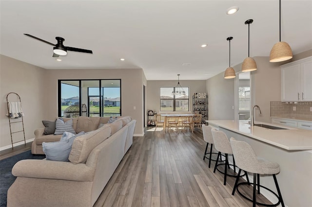 living room featuring plenty of natural light, sink, ceiling fan, and light hardwood / wood-style flooring