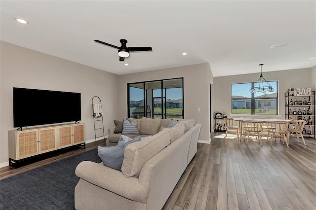 living room with hardwood / wood-style flooring, a healthy amount of sunlight, and ceiling fan with notable chandelier