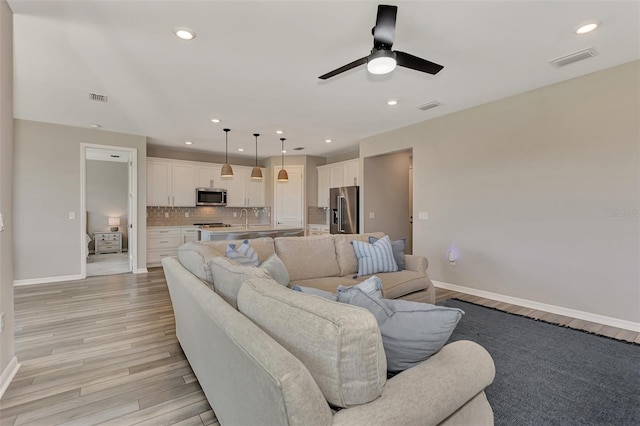 living room with ceiling fan, sink, and light hardwood / wood-style floors