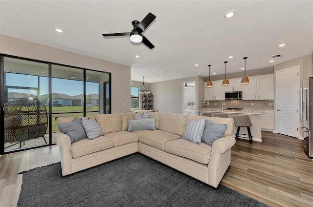 living room featuring light hardwood / wood-style floors, ceiling fan, and a wealth of natural light