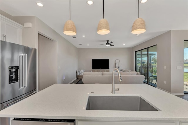 kitchen with an island with sink, sink, decorative light fixtures, and appliances with stainless steel finishes