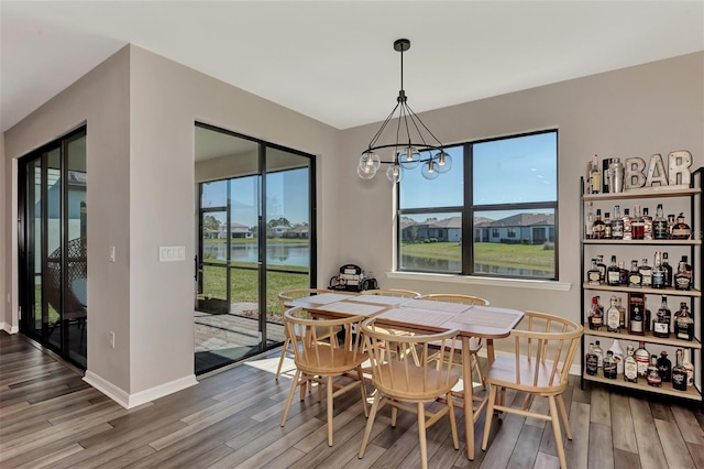 dining area with plenty of natural light, wood-type flooring, and an inviting chandelier