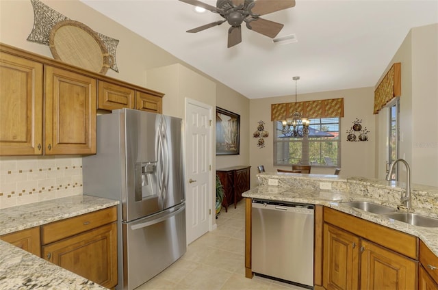 kitchen featuring stainless steel appliances, sink, light stone counters, light tile patterned floors, and decorative light fixtures