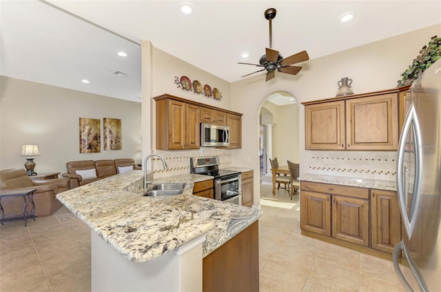 kitchen featuring stainless steel appliances, backsplash, light stone countertops, sink, and kitchen peninsula