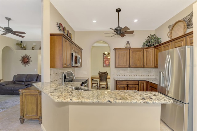 kitchen featuring tasteful backsplash, light stone counters, stainless steel appliances, sink, and kitchen peninsula