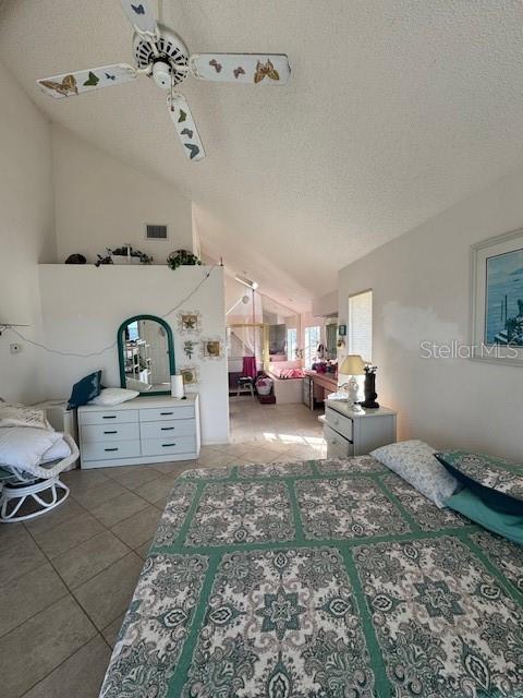 tiled bedroom with ceiling fan, lofted ceiling, and a textured ceiling