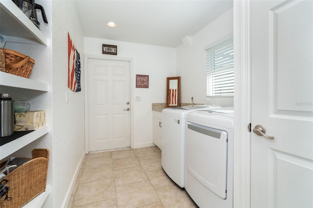 laundry room featuring cabinets, light tile patterned floors, and washing machine and clothes dryer