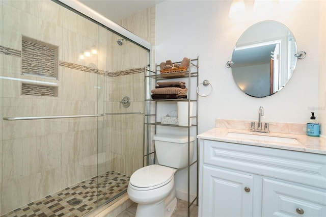 bathroom featuring tile patterned flooring, vanity, toilet, and walk in shower