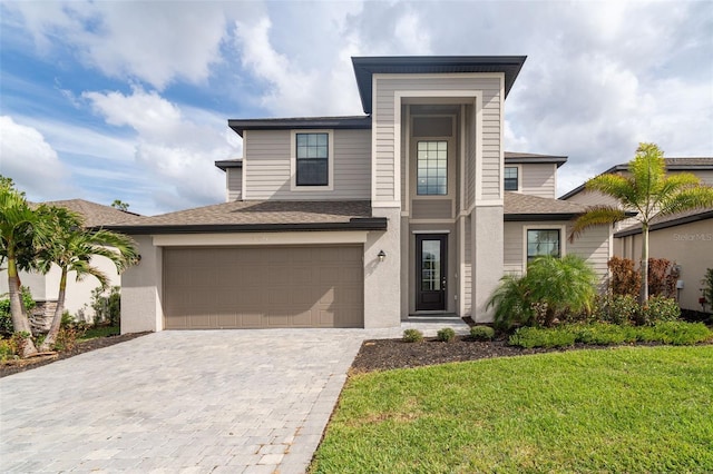 view of front of home featuring stucco siding, a shingled roof, and decorative driveway