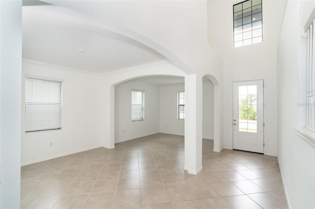 tiled entryway featuring ornamental molding and a high ceiling