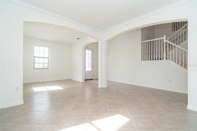 empty room featuring crown molding, light tile patterned floors, baseboards, and arched walkways