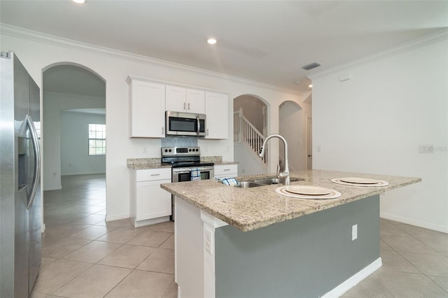 kitchen with a kitchen island with sink, stainless steel appliances, ornamental molding, and white cabinets