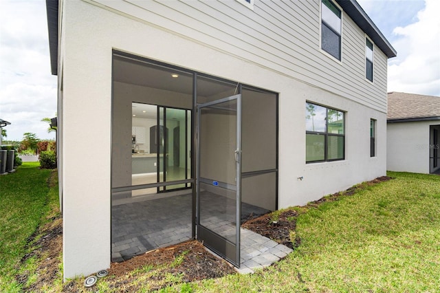 exterior space with central air condition unit, a sunroom, and a lawn