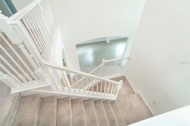 stairway with carpet flooring and a towering ceiling