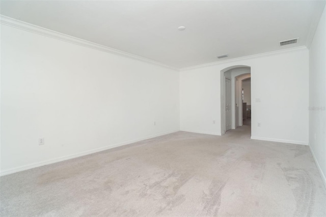 unfurnished room with visible vents, ornamental molding, arched walkways, baseboards, and light colored carpet