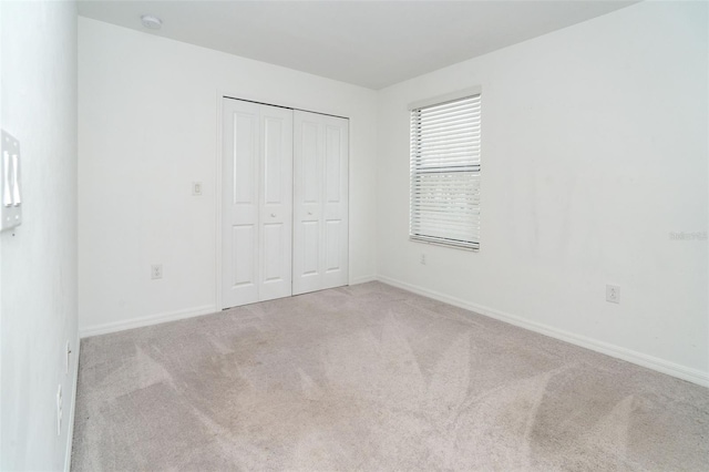 unfurnished bedroom featuring light carpet and a closet