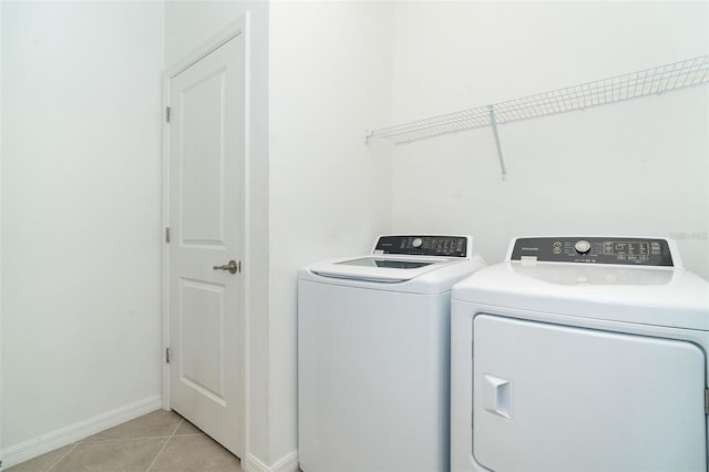 laundry area with washer and dryer, baseboards, laundry area, and light tile patterned floors