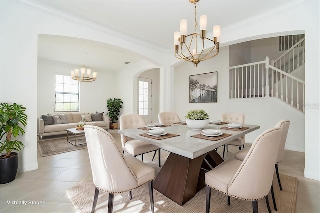 dining space with a notable chandelier, ornamental molding, stairway, arched walkways, and light tile patterned flooring