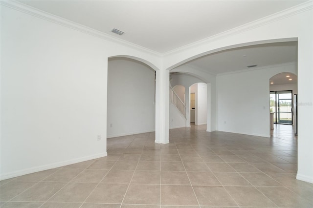 empty room with visible vents, ornamental molding, arched walkways, light tile patterned floors, and baseboards