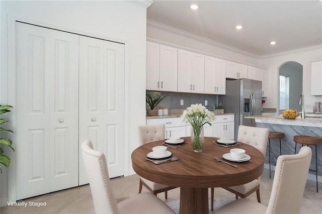 dining area featuring arched walkways, recessed lighting, crown molding, and light tile patterned flooring