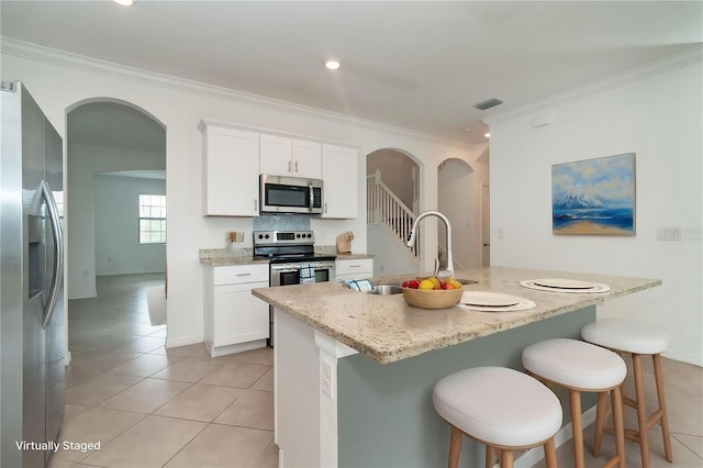 kitchen featuring visible vents, crown molding, arched walkways, stainless steel appliances, and a sink