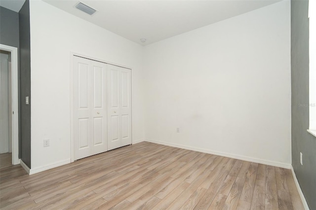 unfurnished bedroom with light wood-style floors, visible vents, a closet, and baseboards