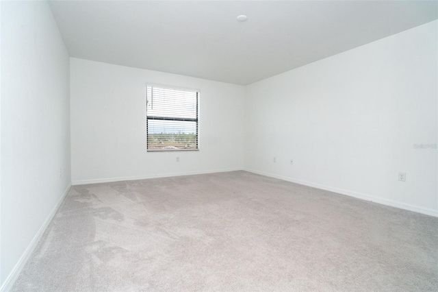 empty room with baseboards and light carpet