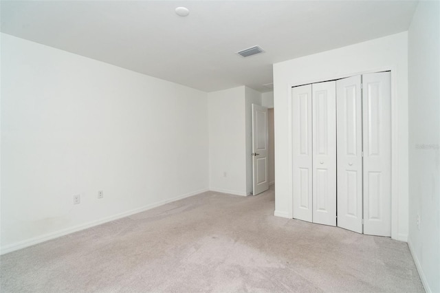 unfurnished bedroom featuring visible vents, baseboards, light colored carpet, and a closet