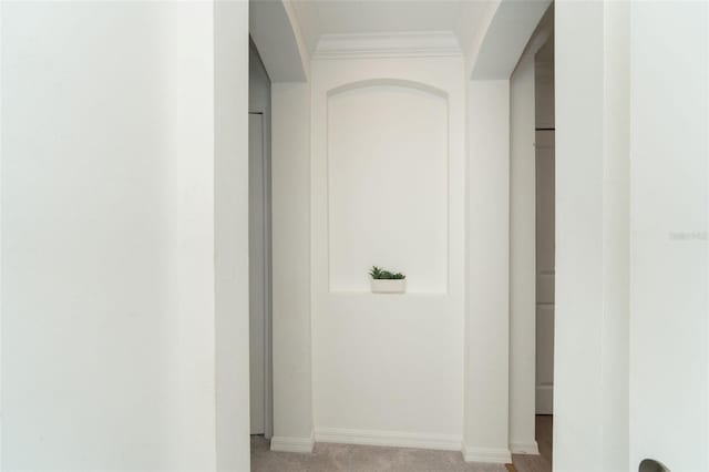 hallway with baseboards, light colored carpet, and ornamental molding