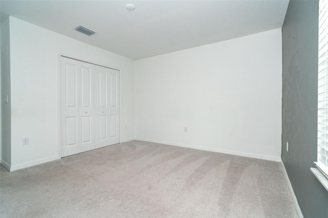 unfurnished bedroom featuring visible vents, baseboards, a closet, and carpet flooring