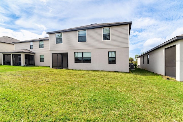 rear view of property featuring stucco siding, a lawn, and a sunroom