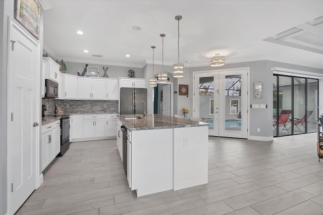 kitchen featuring stainless steel appliances, hanging light fixtures, a kitchen island with sink, white cabinets, and french doors