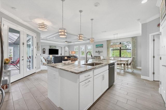 kitchen featuring a center island with sink, white cabinetry, sink, light stone counters, and stainless steel dishwasher