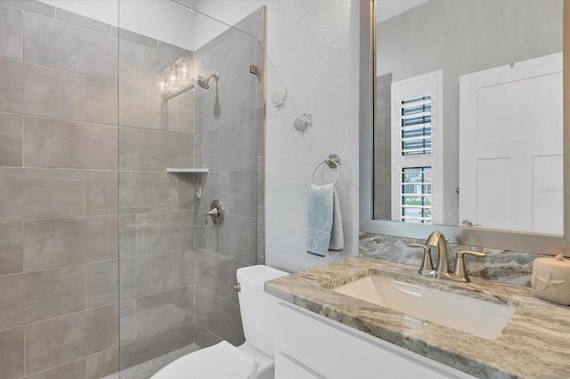 bathroom with toilet, vanity, and a tile shower