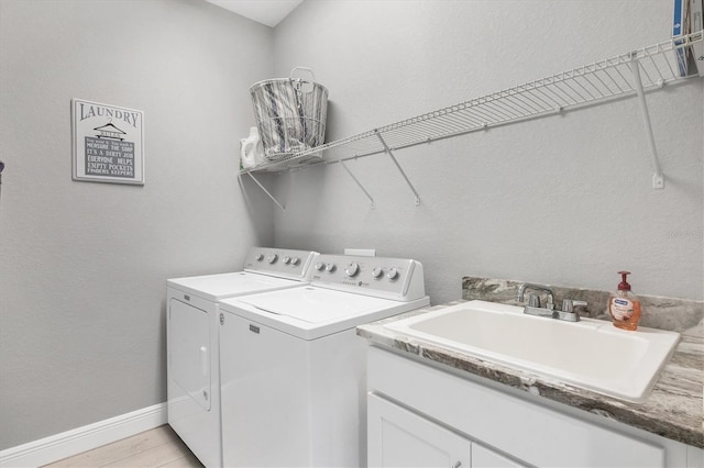 laundry room with light hardwood / wood-style floors, sink, and washer and dryer