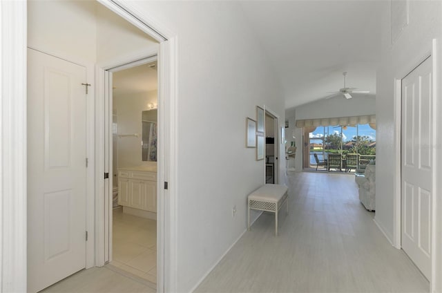 corridor with light hardwood / wood-style flooring and vaulted ceiling