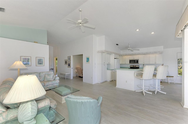 living room featuring ceiling fan, light hardwood / wood-style flooring, and high vaulted ceiling