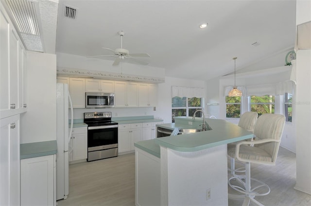 kitchen with lofted ceiling, sink, light wood-type flooring, an island with sink, and stainless steel appliances