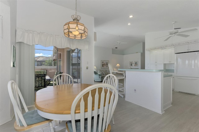 dining room featuring light wood-type flooring, vaulted ceiling, and sink