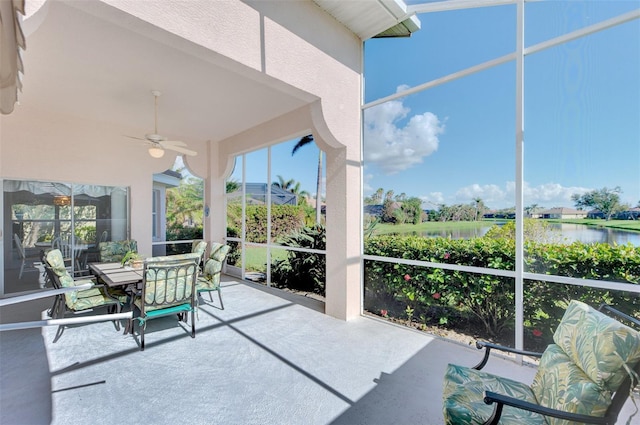 sunroom with ceiling fan and a water view