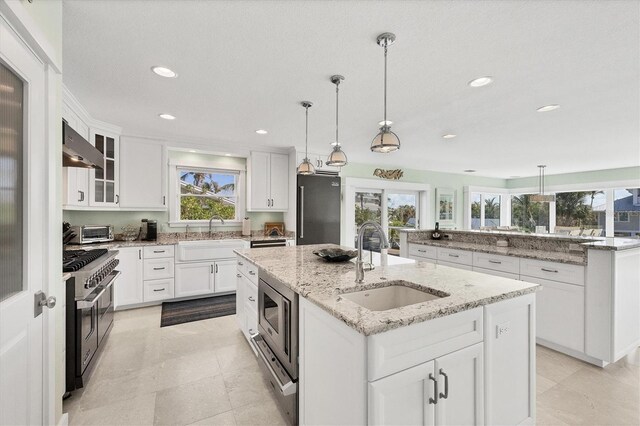 kitchen featuring white cabinets, sink, an island with sink, and high end appliances