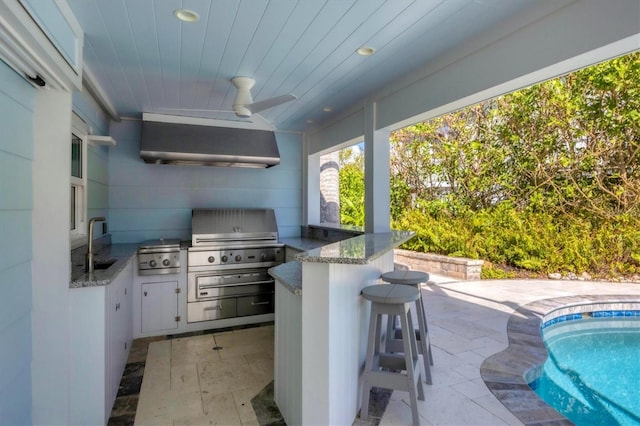 view of patio / terrace with area for grilling, ceiling fan, an outdoor kitchen, and a wet bar