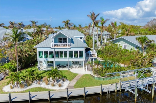 back of house featuring a balcony, a lawn, a patio area, and a water view