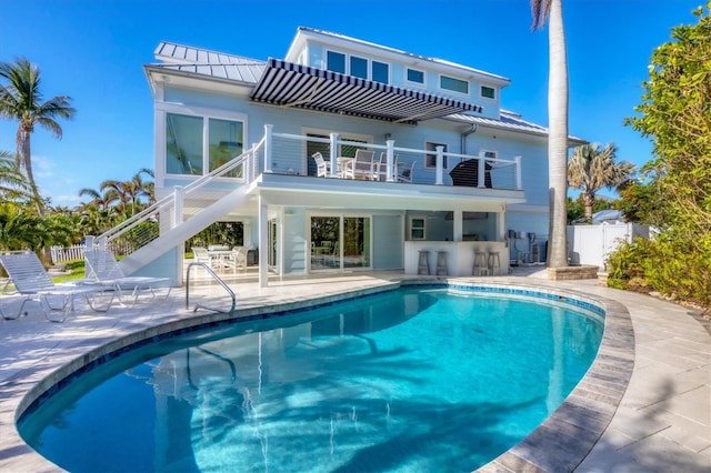 back of property with exterior bar, a patio, a fenced in pool, and a balcony