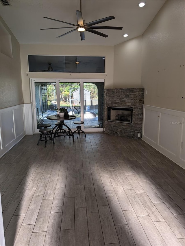 unfurnished living room featuring a fireplace, ceiling fan, and dark wood-type flooring